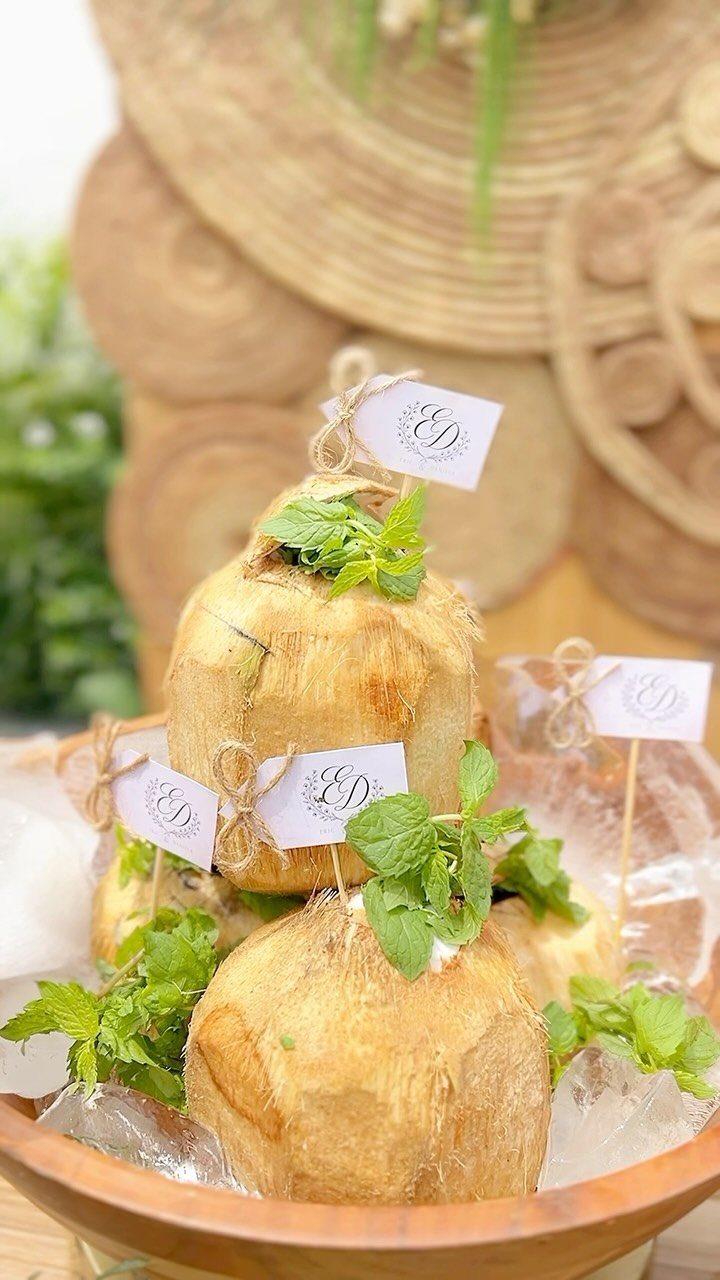 Fresh coconuts with mint leaves chilled in a wooden bowl of ice.