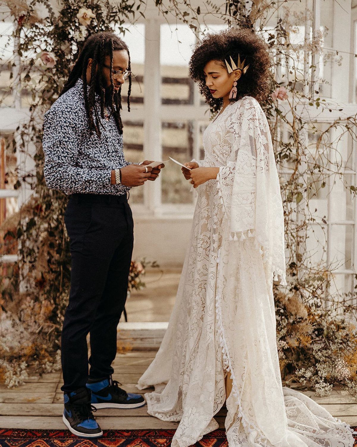 Couple under floral arch, woman wearing a long white bohemian lace wedding dress