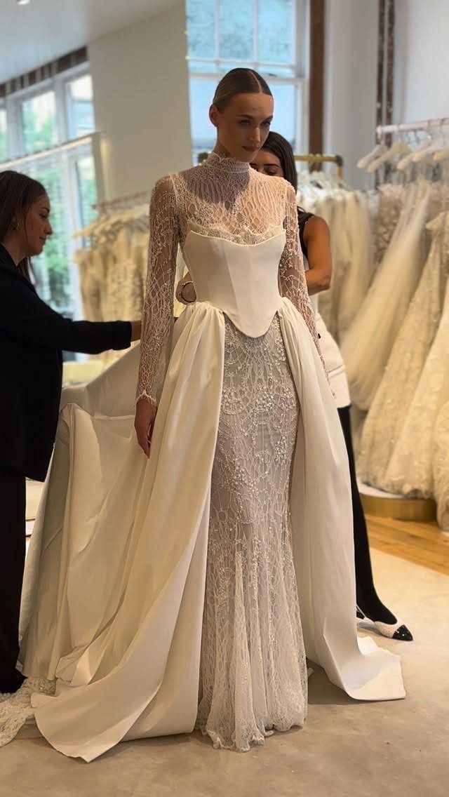 Woman wearing a white bridal gown with a detachable overskirt in a boutique.