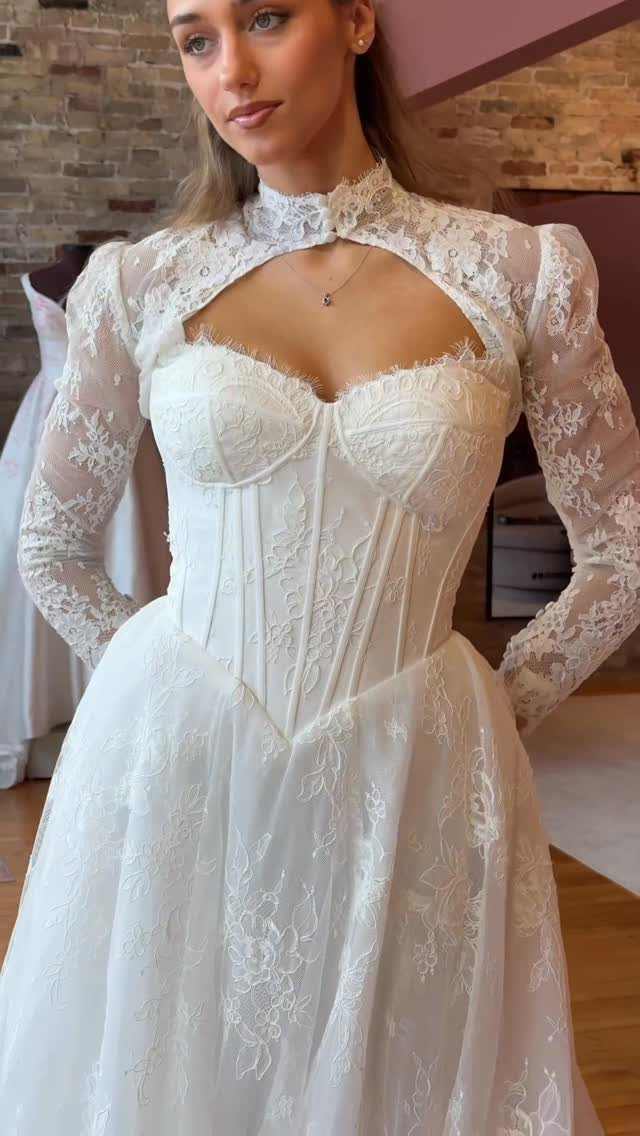 Woman in a white lace wedding dress with a corset bodice and cutout neckline.