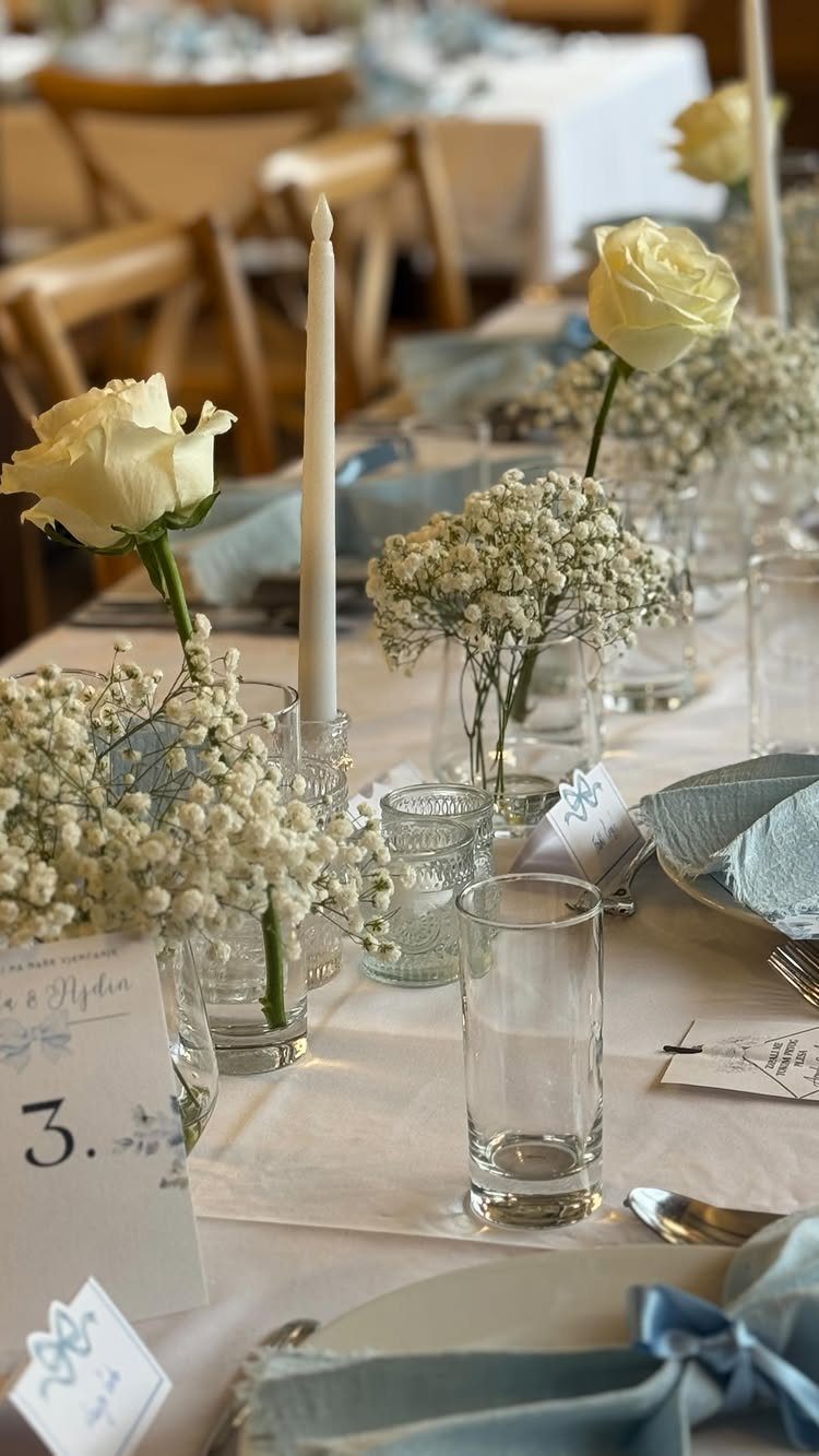 Wedding table setting with white roses, baby's breath, and light blue napkins.