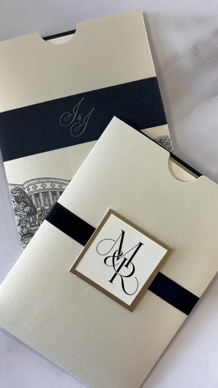Cream wedding invitation envelopes with navy blue bands and a monogrammed card.