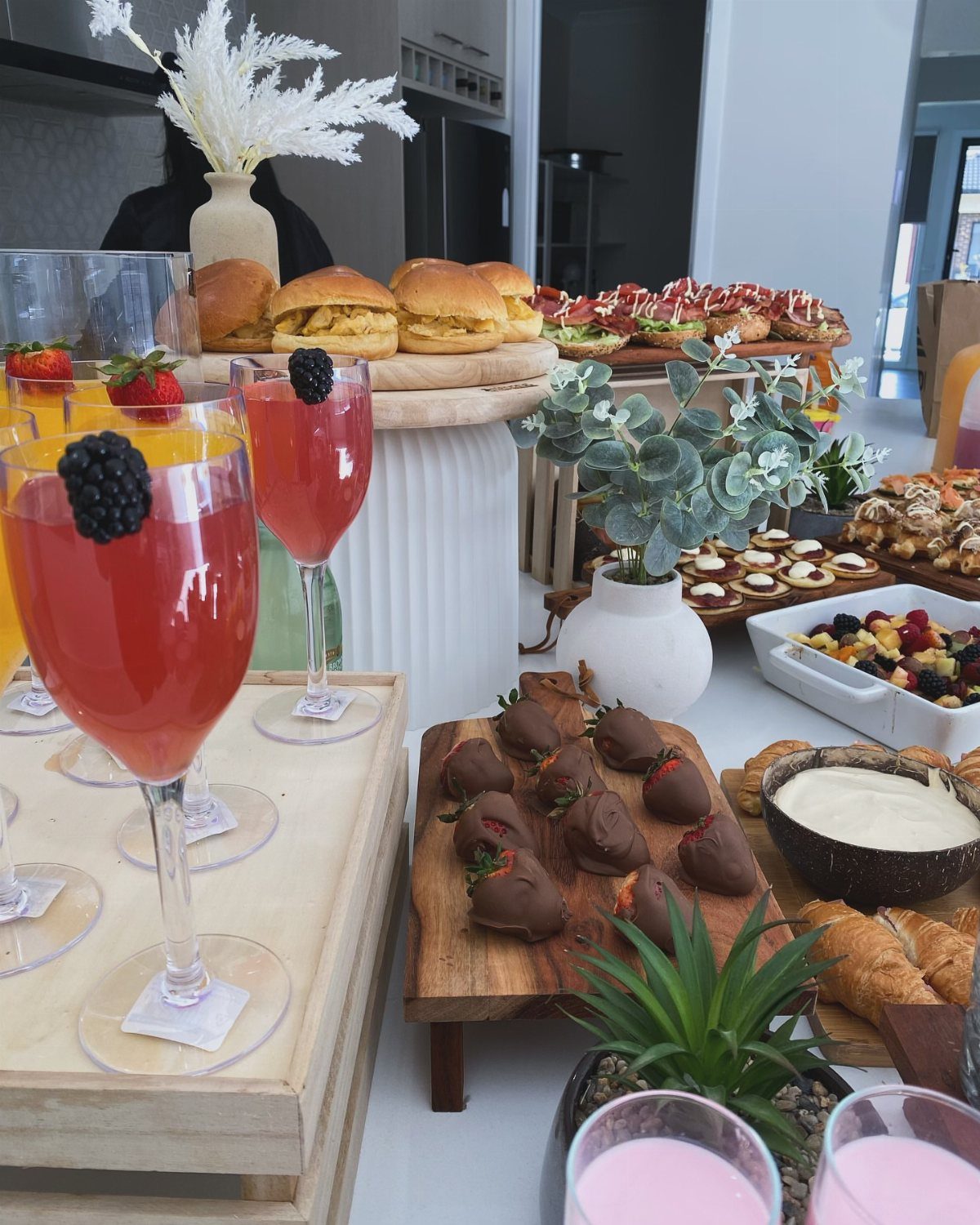Buffet table with red cocktails, chocolate strawberries, and sliders for a small celebration.