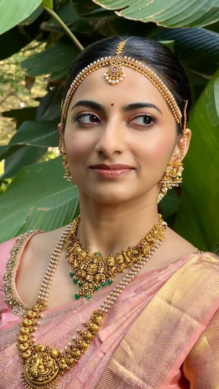 South Indian bride in pink silk saree and ornate gold bridal jewelry