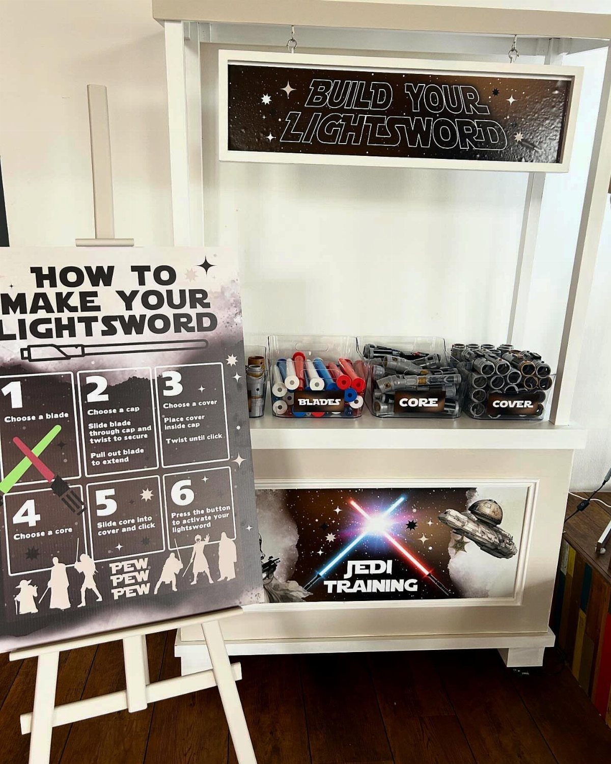 Star Wars themed lightsaber building station with instructional signs and plastic parts.