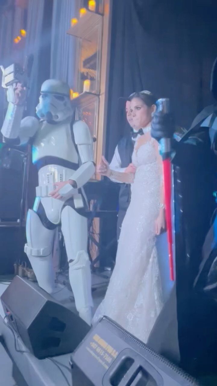 Bride in white dress posing with a Stormtrooper and a red lightsaber
