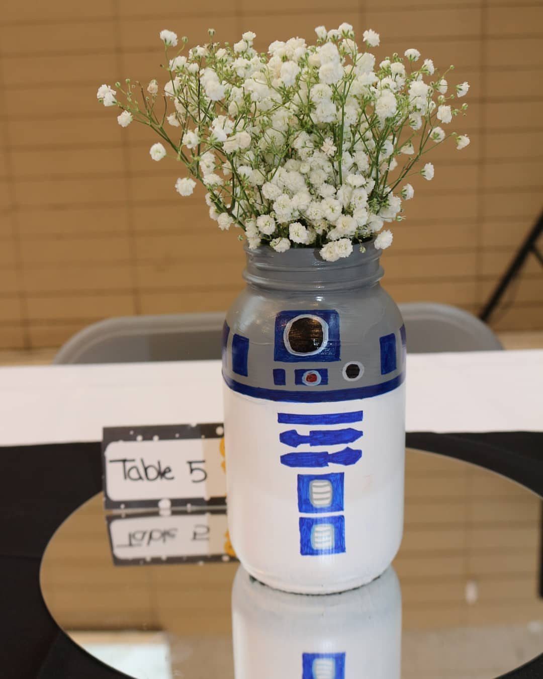 R2-D2 painted mason jar vase with white baby's breath on a mirrored table