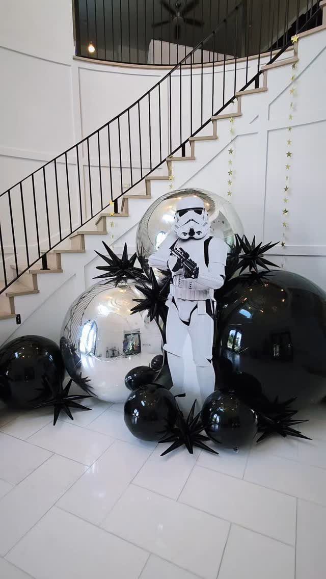 Stormtrooper cutout surrounded by silver and black balloons at the base of stairs.