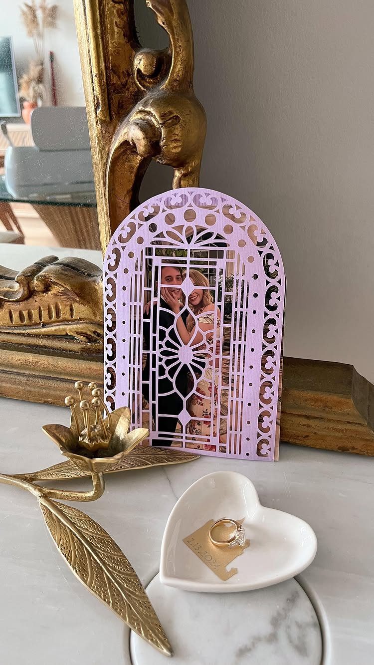 Purple laser-cut announcement card with couple's photo and an engagement ring in heart dish.