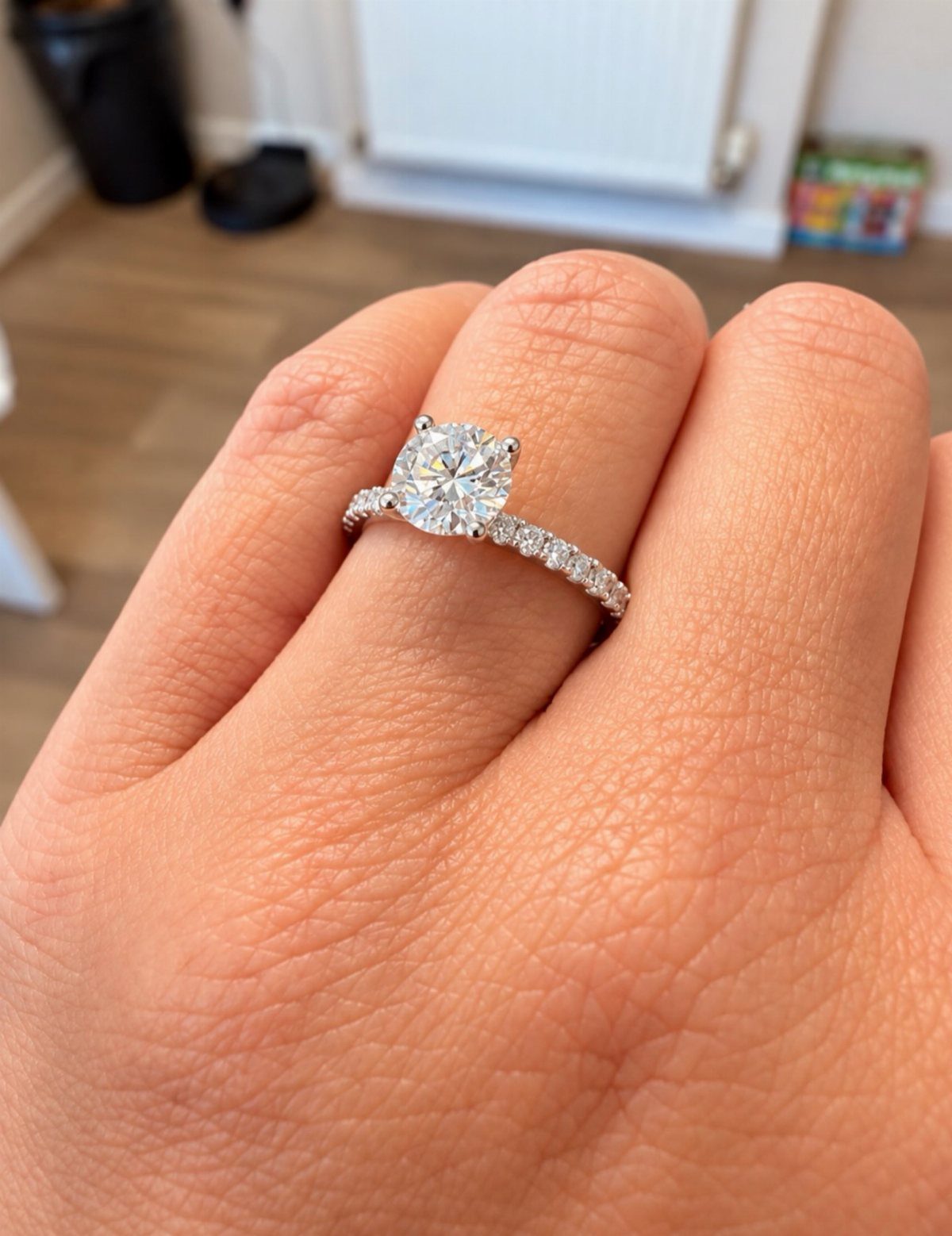 Diamond engagement ring with a round center stone on a person's finger.