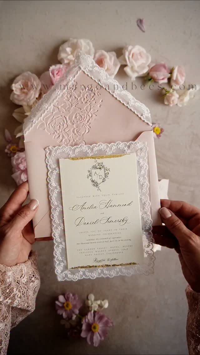 Wedding invitation with elegant calligraphy in a lace frame and pink envelope.