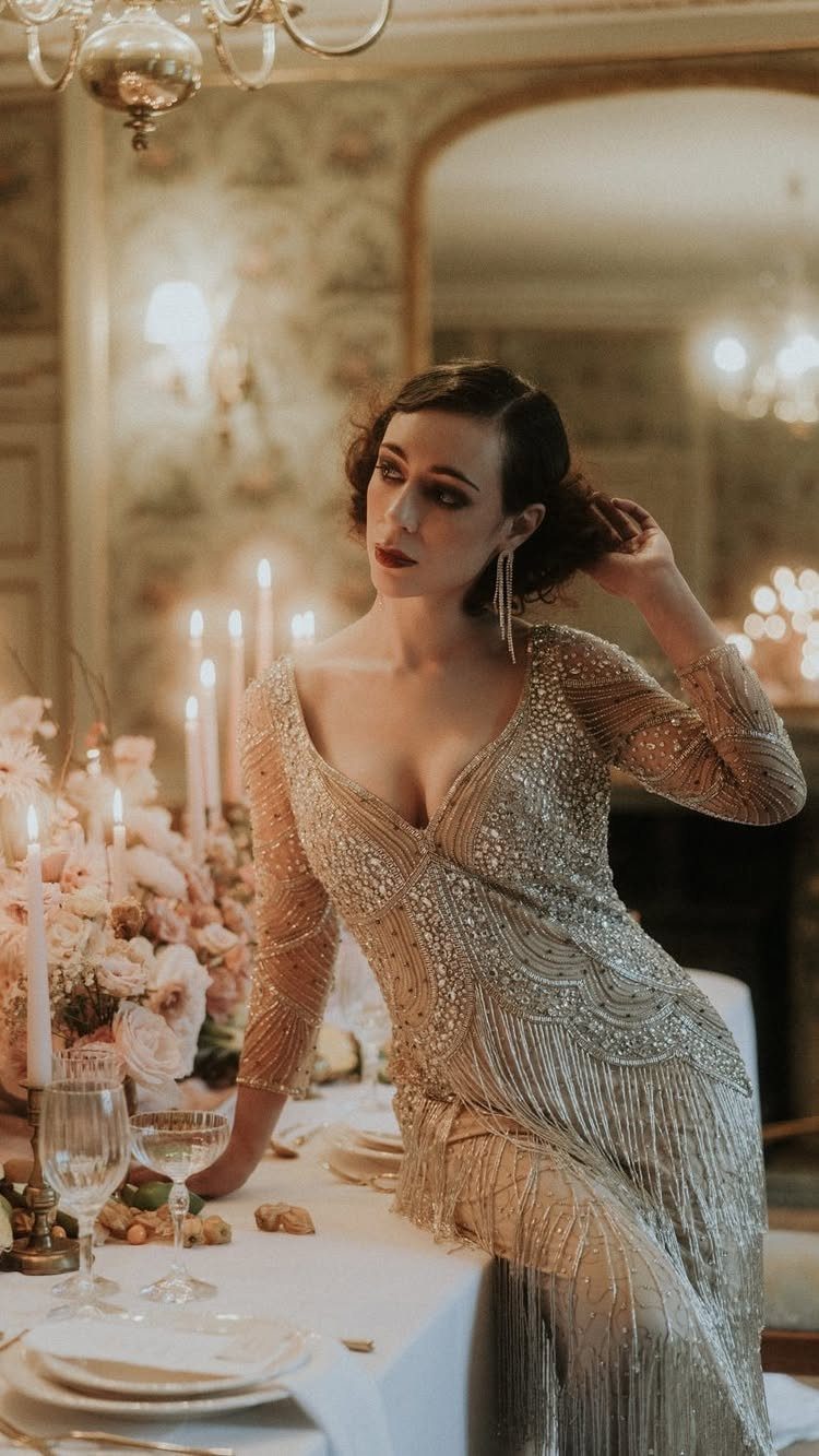 Woman in a gold sequined gown posing at a candlelit vintage dinner table