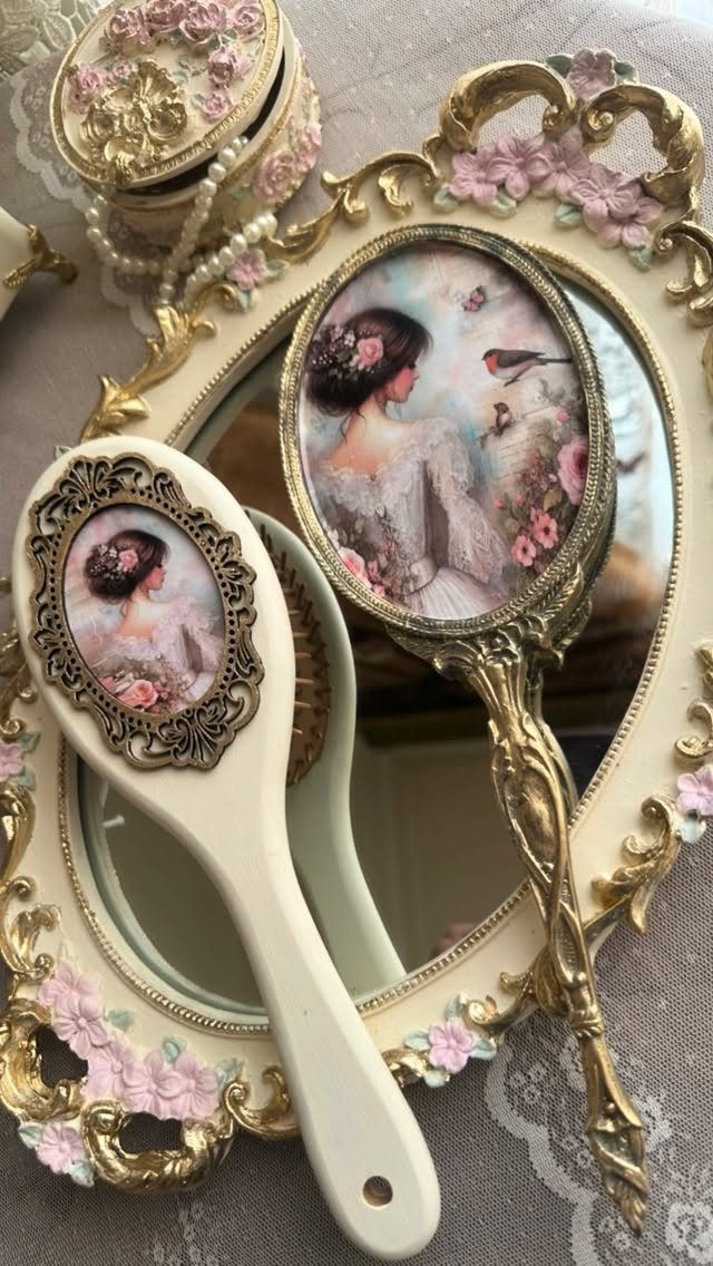 Vintage vanity set with gold-framed mirrors and hairbrush featuring romantic painted portraits.