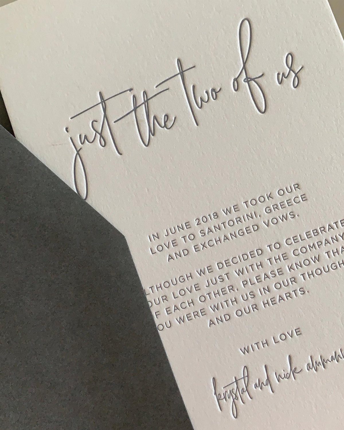 White embossed wedding announcement card stating a private ceremony in Santorini, Greece.