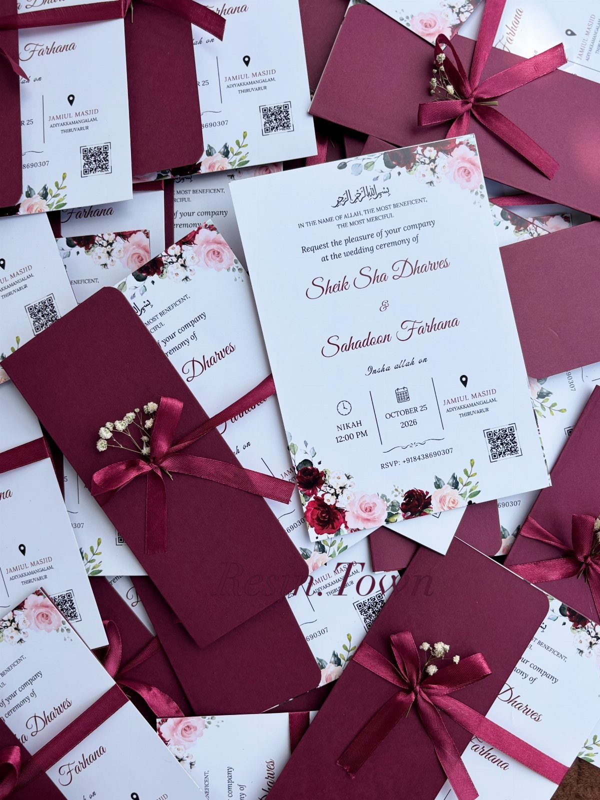 Wedding invitations with burgundy envelopes, floral accents, and elegant script on white cards.