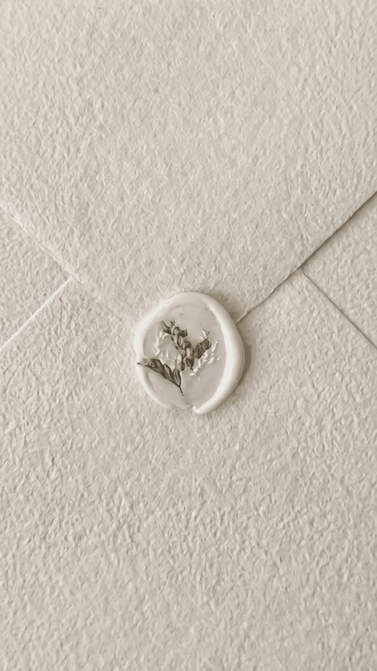 Cream textured envelope sealed with a white wax seal and dried flower sprig.
