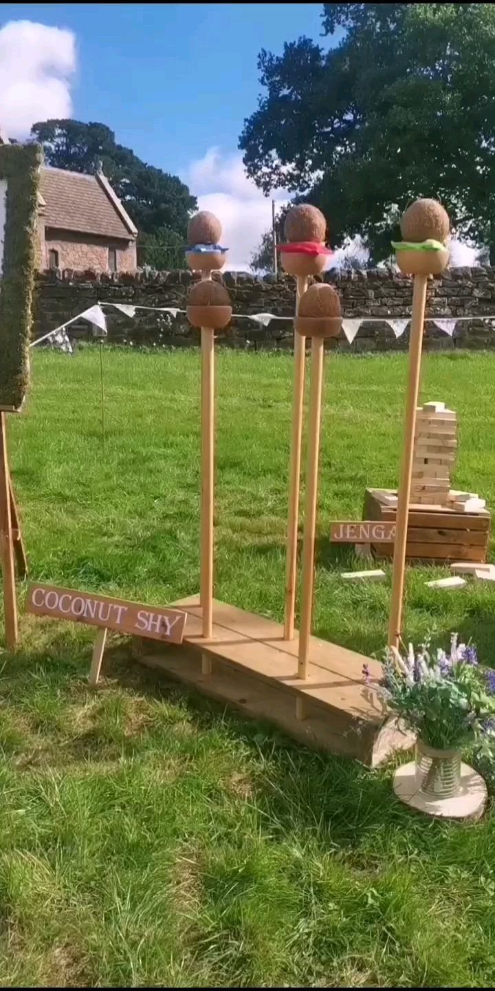 Wooden coconut shy and jenga games set up on a grassy outdoor lawn