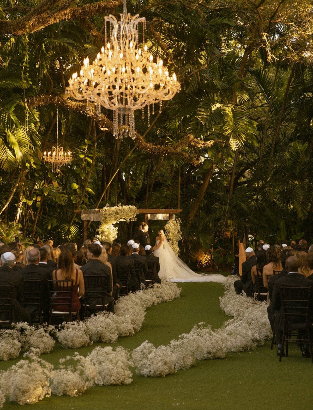 Wedding ceremony in a park with a crystal chandelier hanging from a tree branch