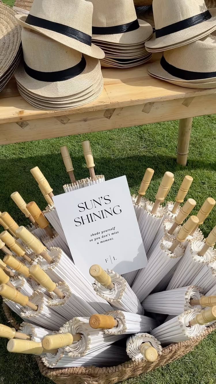 White umbrellas in a basket and straw hats on a table for guests.