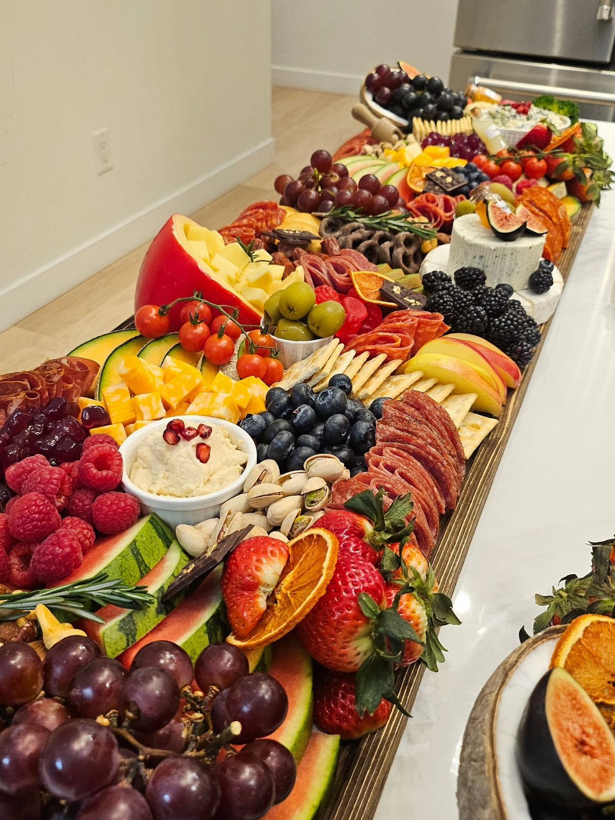 Lavish charcuterie board with assorted fruits, cheeses, and meats on a white countertop