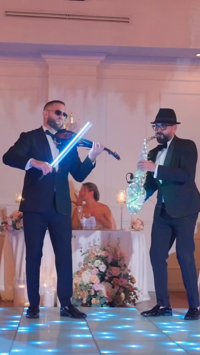 Musicians playing LED violin and saxophone on a glowing dance floor at a wedding.