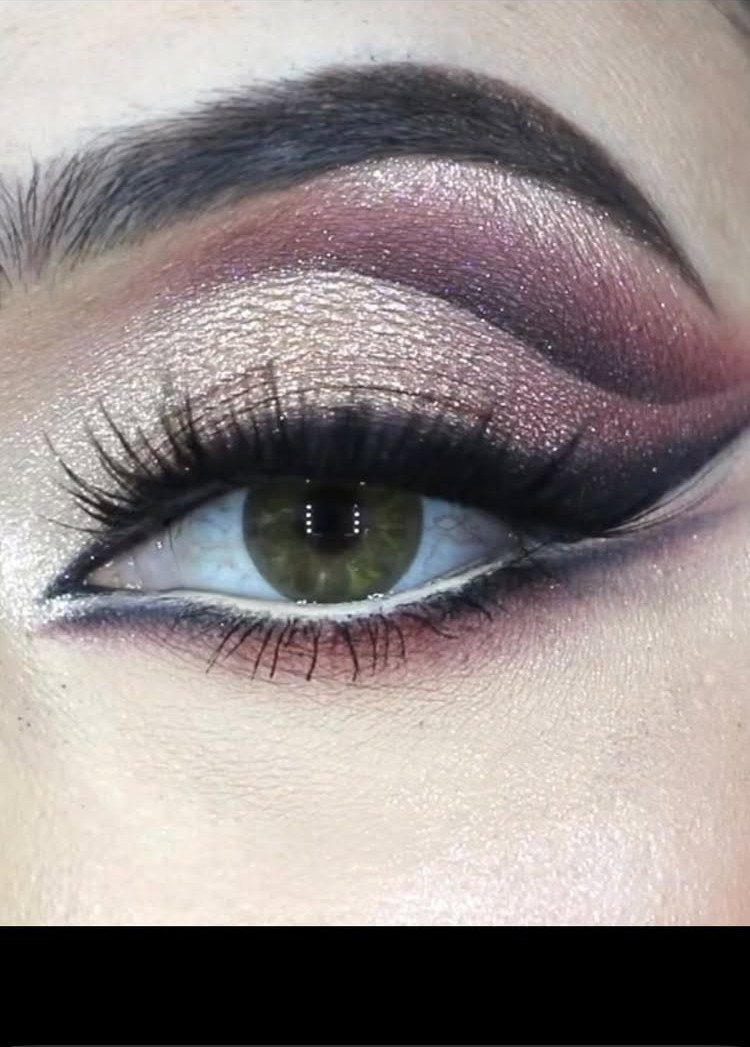 Eye with metallic gold and purple eyeshadow, bold eyeliner, and long lashes.