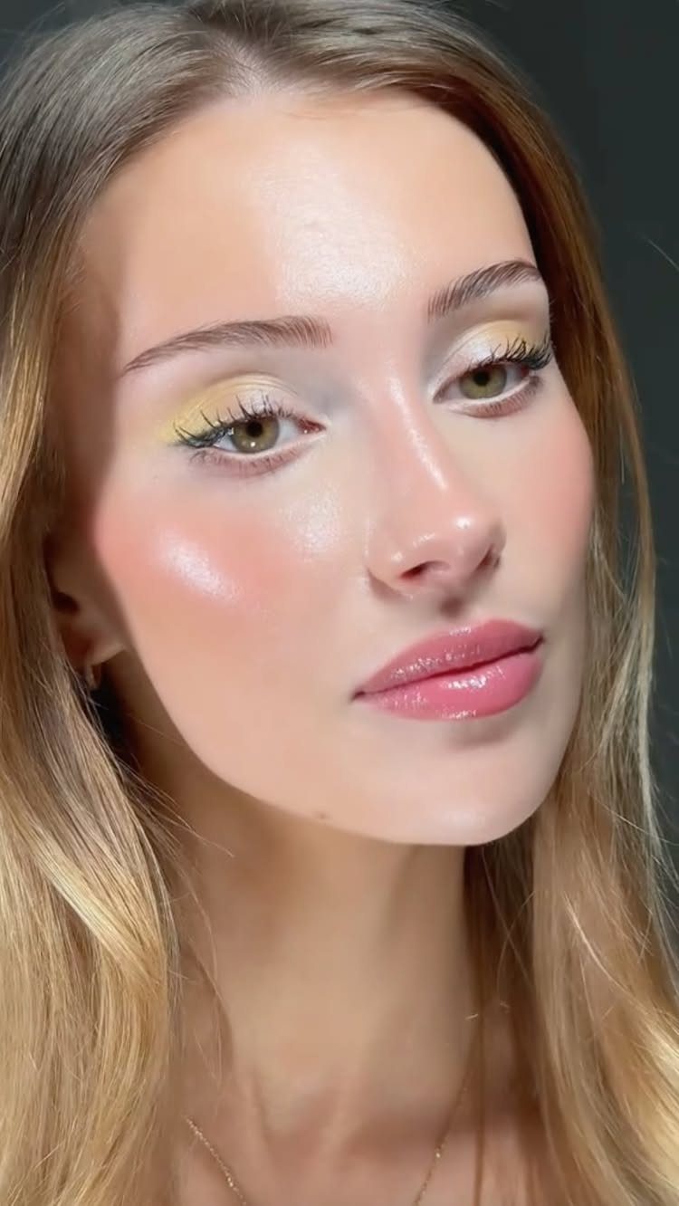 Woman with shimmering gold eyeshadow, glossy pink lips, and glowing skin.