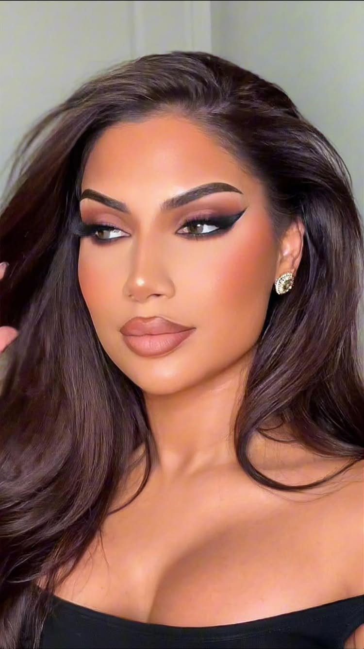 Woman with dramatic smoky eye makeup, winged eyeliner, and long brown hair.