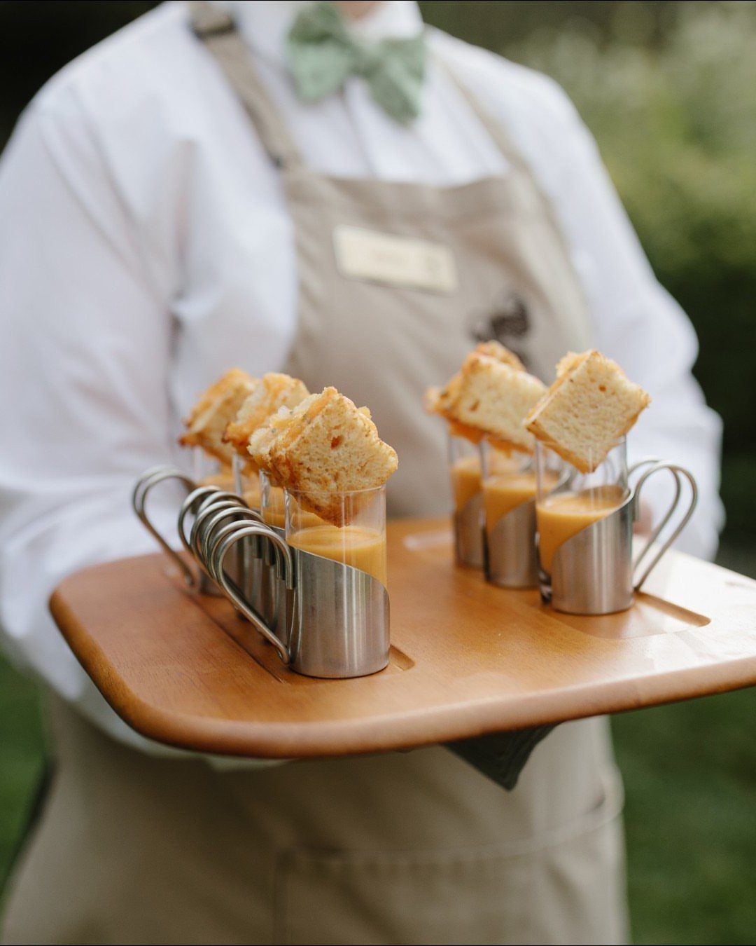 Tomato soup shooters with grilled cheese toast served on a wooden tray