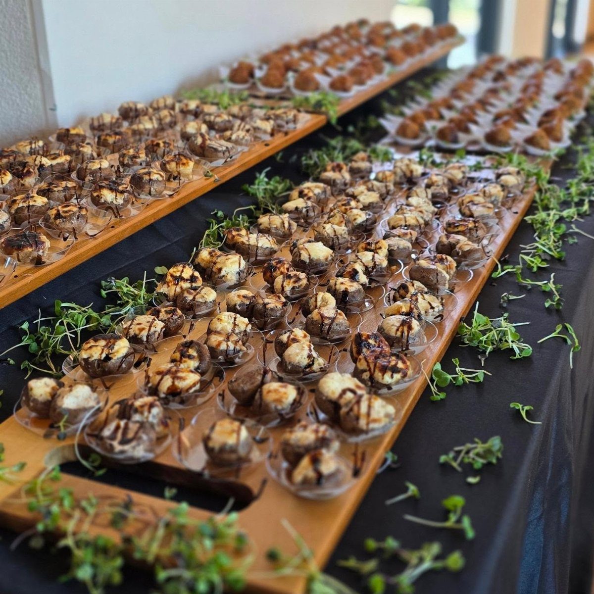Stuffed mushrooms with white cheese and glaze served on wooden platters with microgreens.