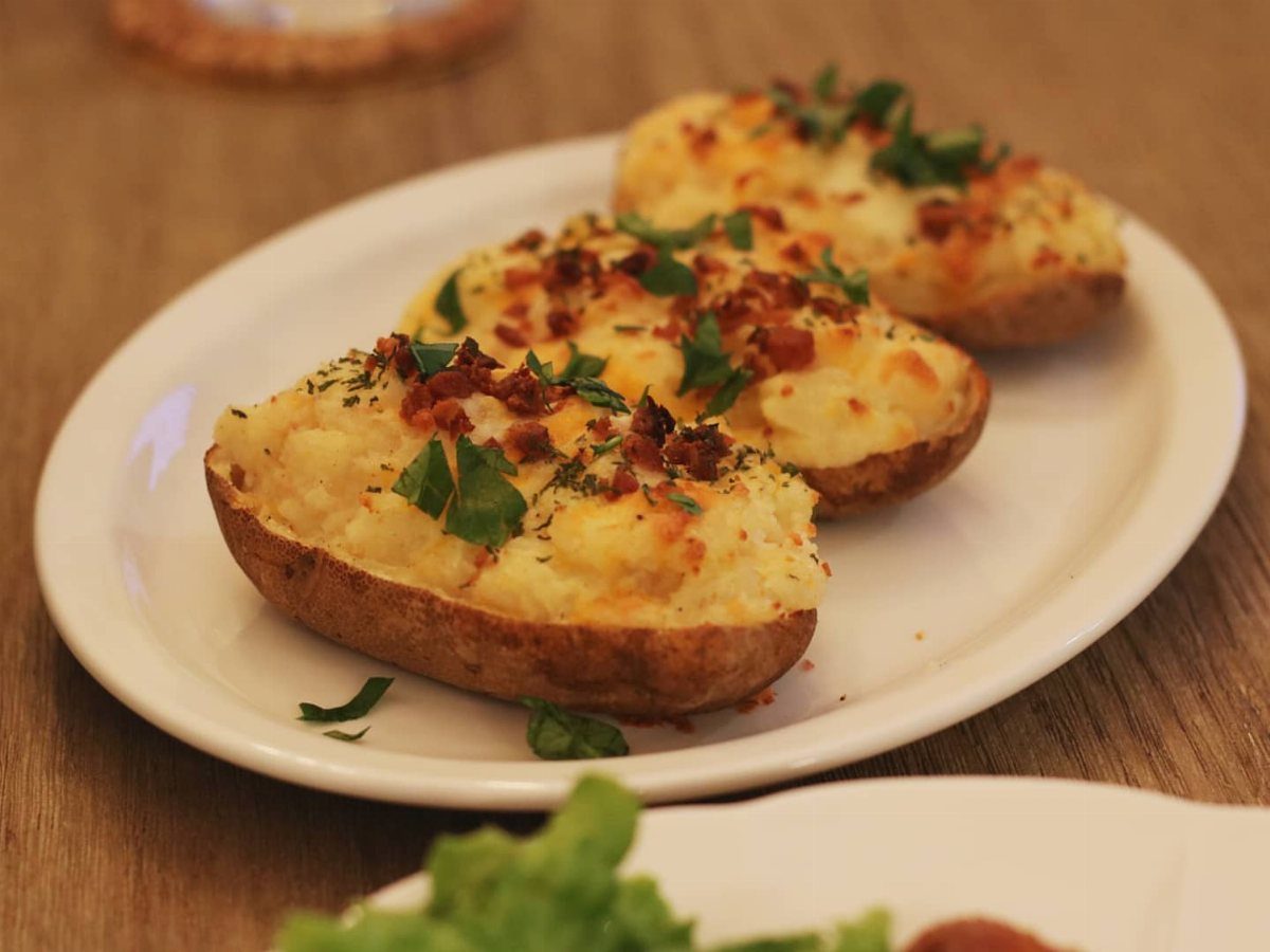 Twice baked potato bites topped with melted cheese, bacon, and fresh green herbs.