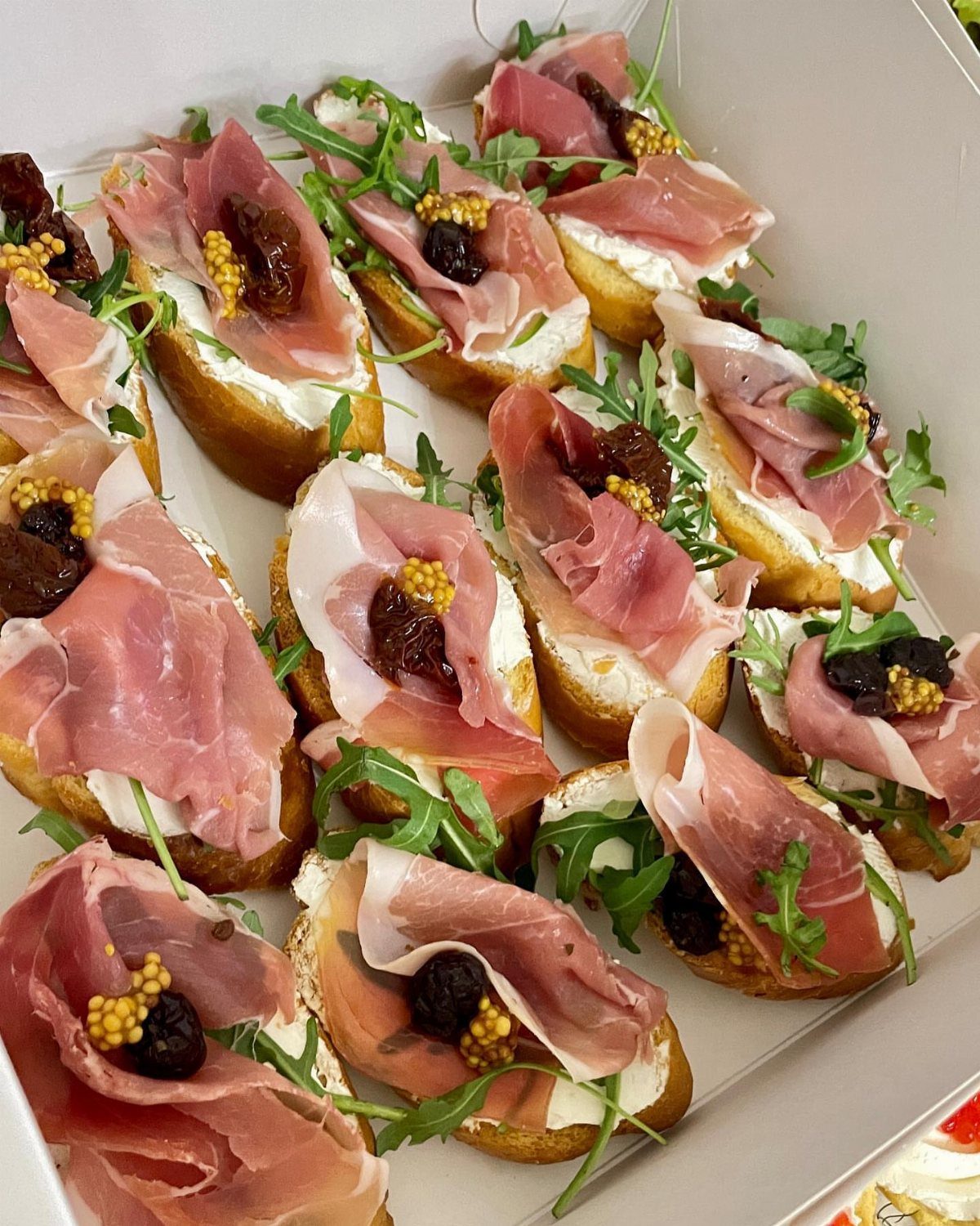 Bruschetta topped with whipped goat cheese, prosciutto, dried cranberries, and fresh arugula.