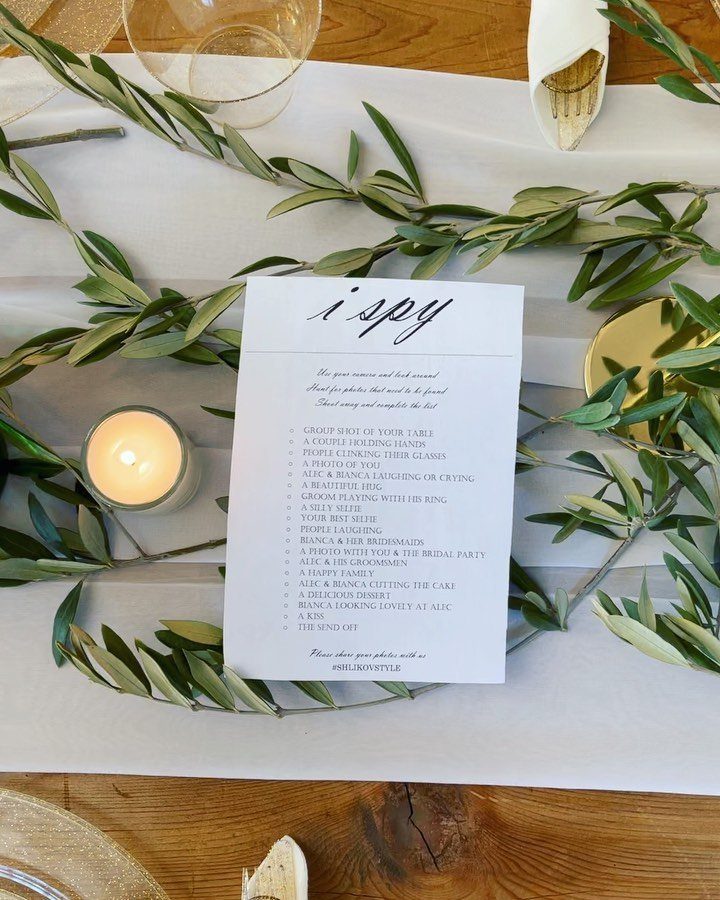 Wedding i spy game card on a table with olive branches and candle.