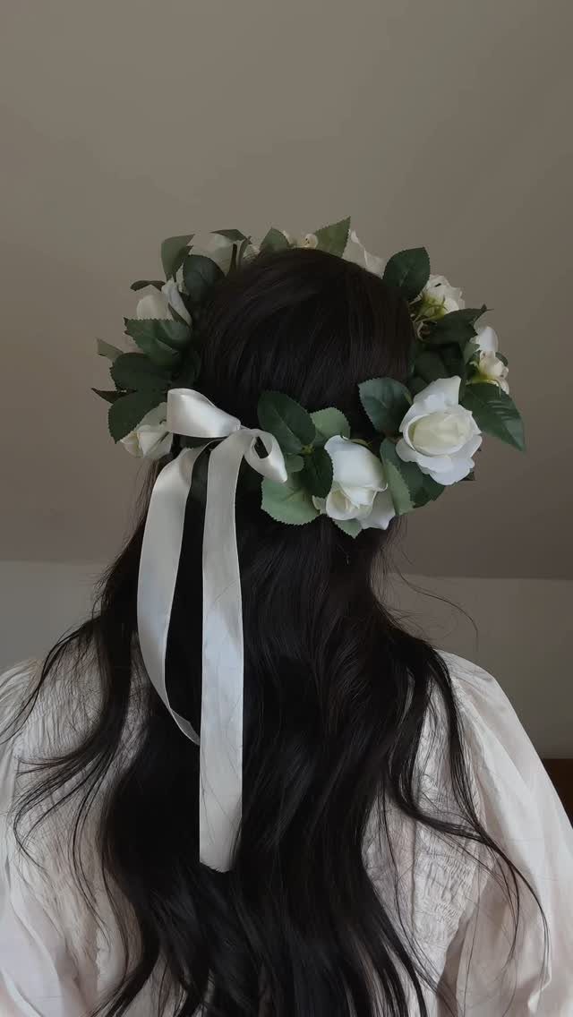 Flower crown of white roses and green leaves on long dark hair
