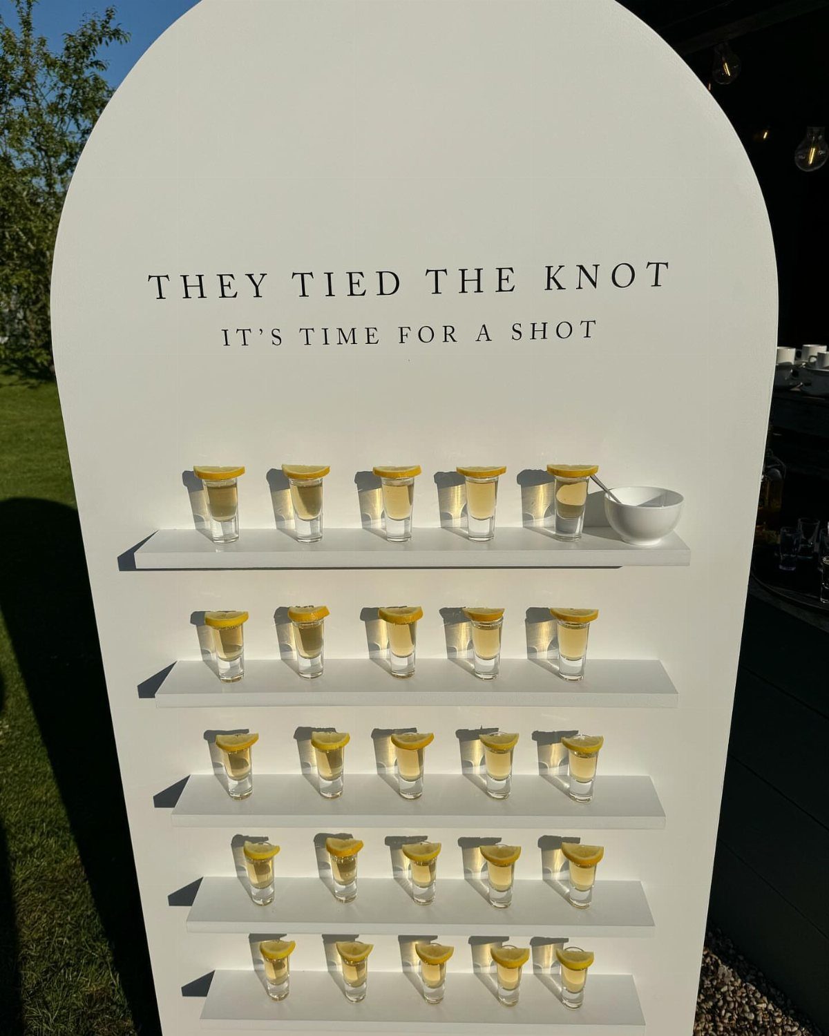 White arched shot glass display with lemon garnished drinks for a wedding celebration