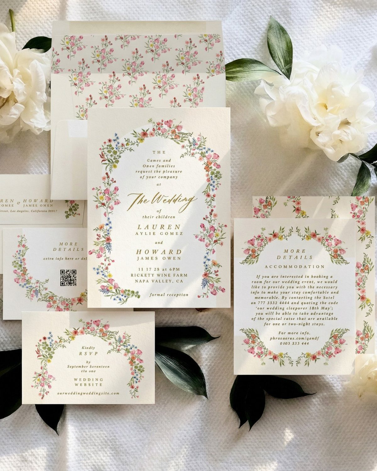 Wedding invitation suite with floral borders surrounded by white peonies and green leaves.