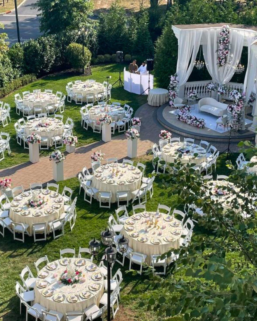 Outdoor wedding reception with cream tables and chairs on a green lawn