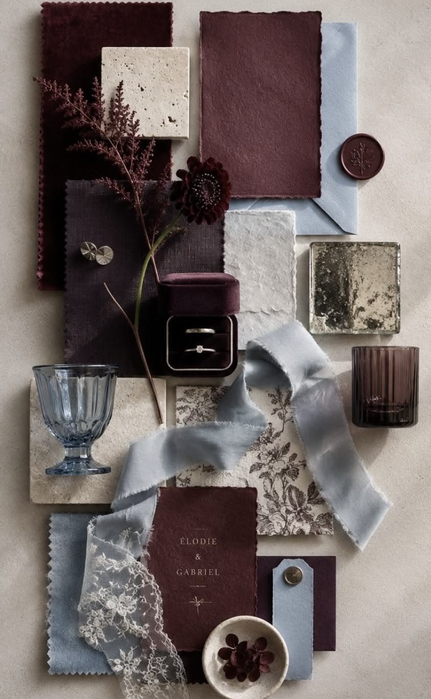 Wedding mood board with burgundy and dusty blue fabric, paper, and accessories.