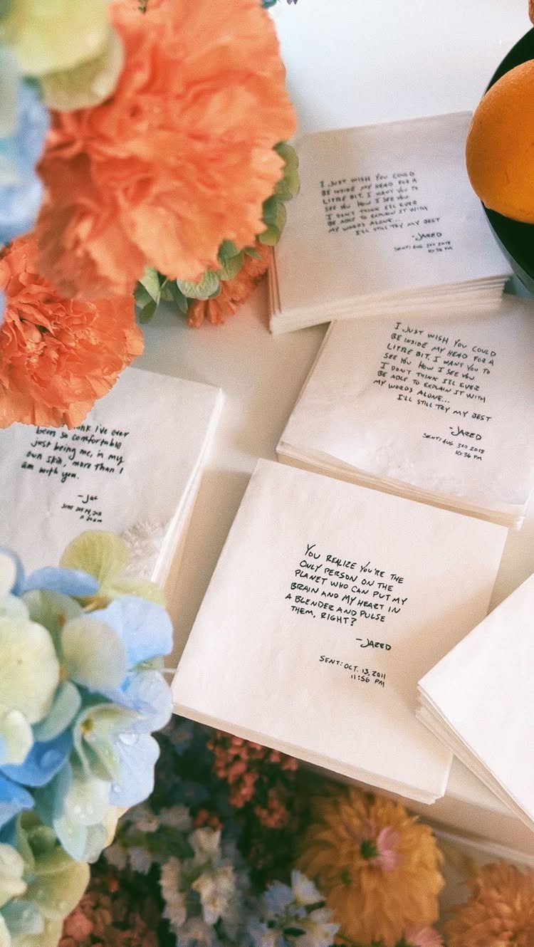 White square napkins with printed romantic quotes surrounded by colorful wedding flowers.