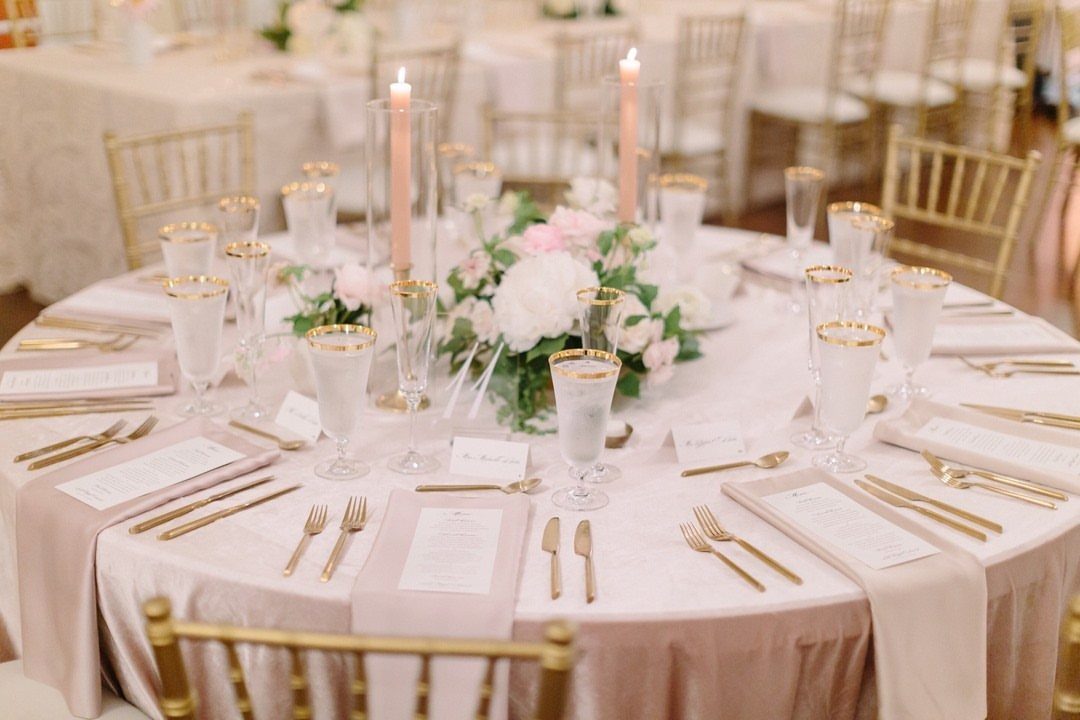 Pale pink napkins draped elegantly off the edge of a wedding table setting.