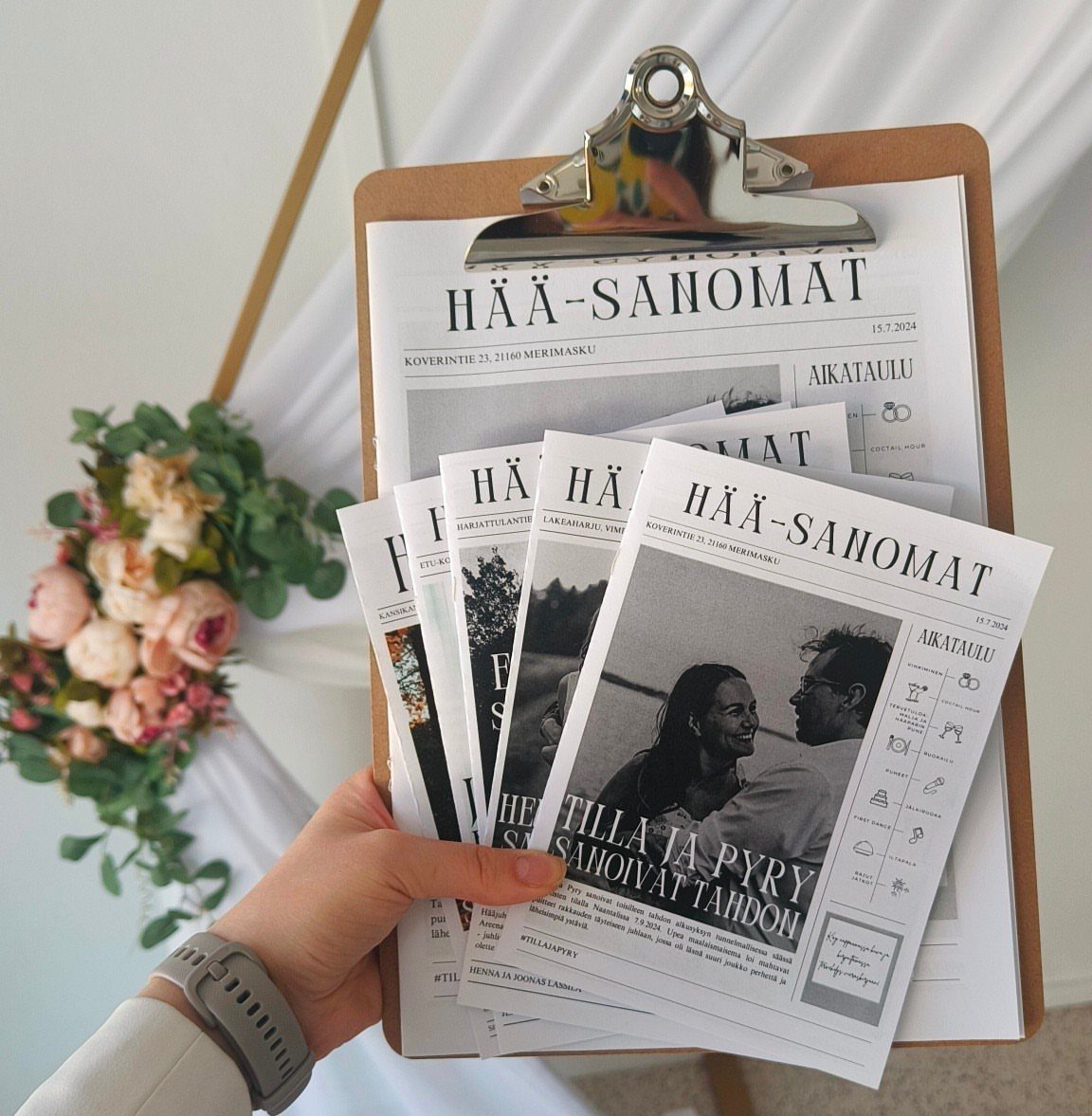 Wedding newspapers on a clipboard featuring a couple's photo and Finnish text.