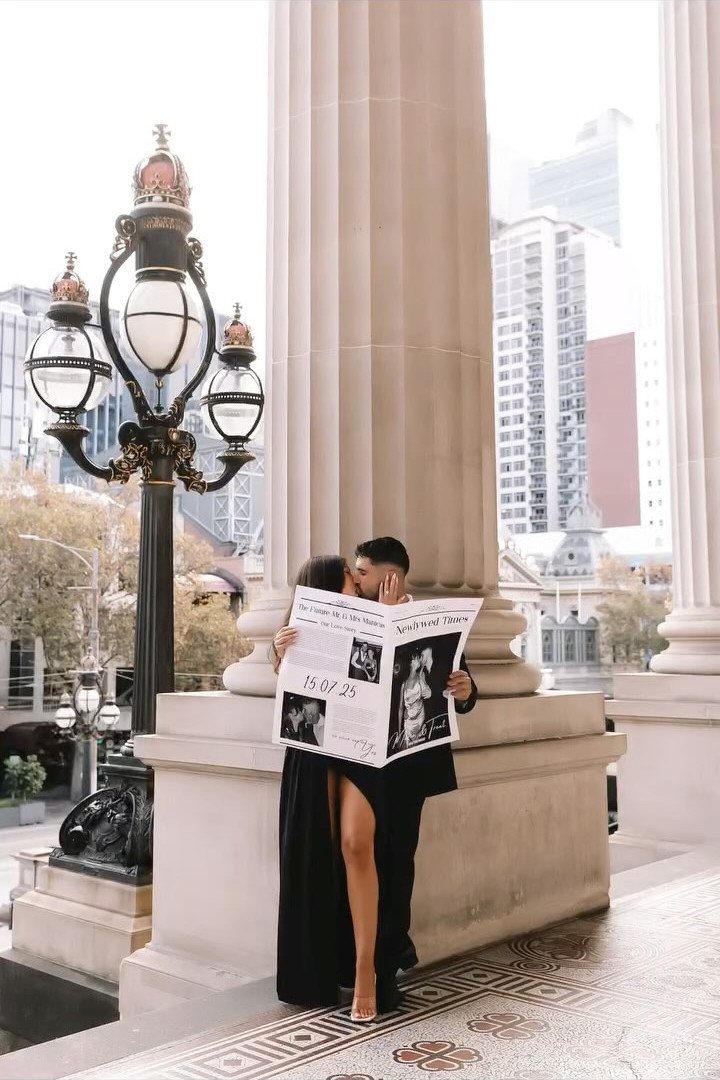 Couple kissing behind a wedding newspaper in front of a classical white column.