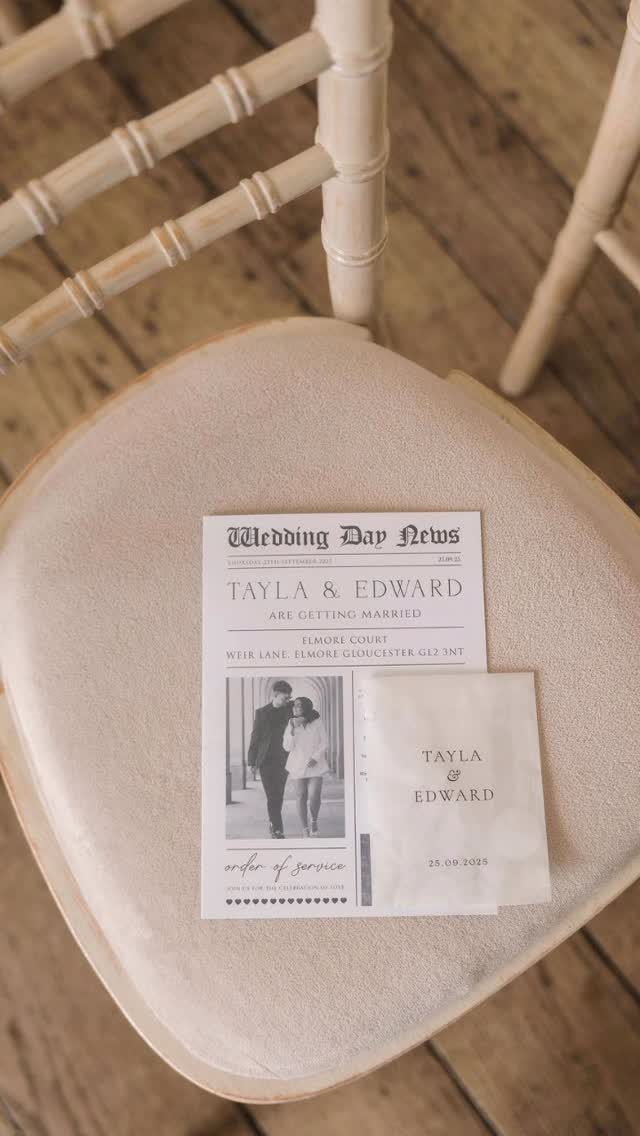 Wedding newspaper and card resting on a beige chair cushion in a room.
