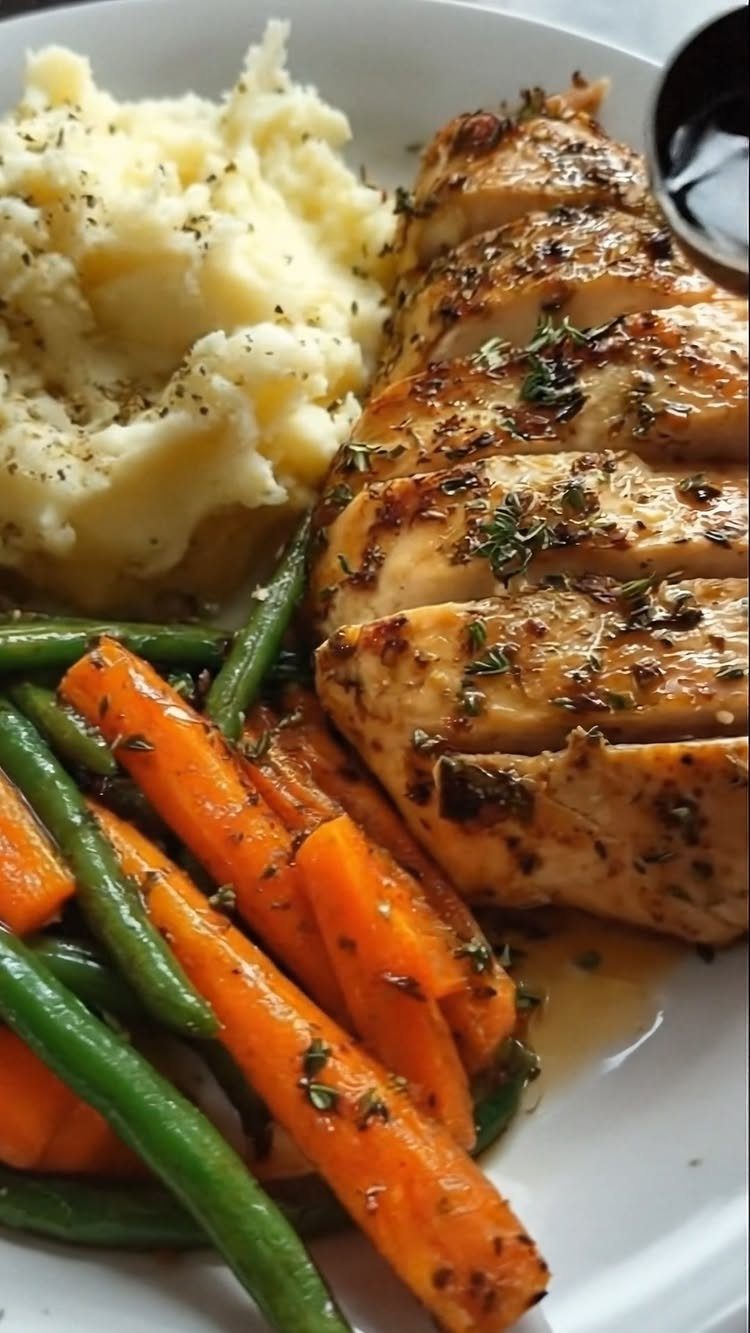 Grilled chicken breast with mashed potatoes, carrots, and green beans on a white plate.