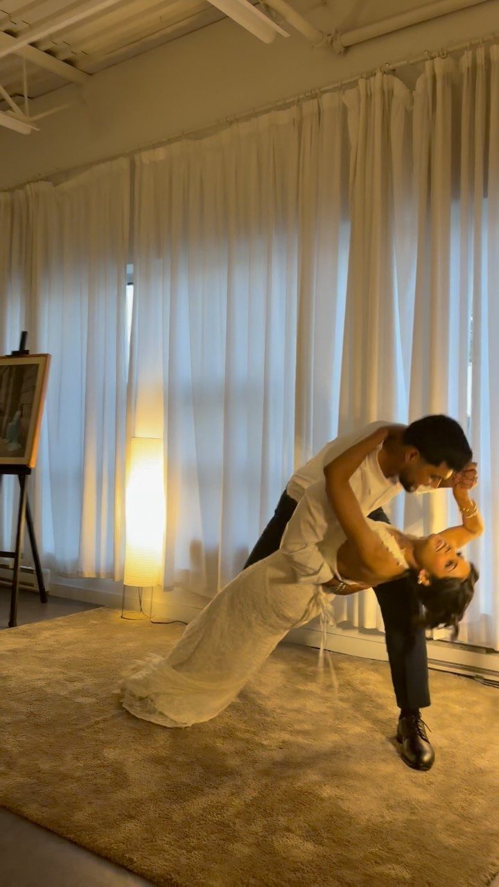 Man dipping a woman in a white wedding dress in a living room.