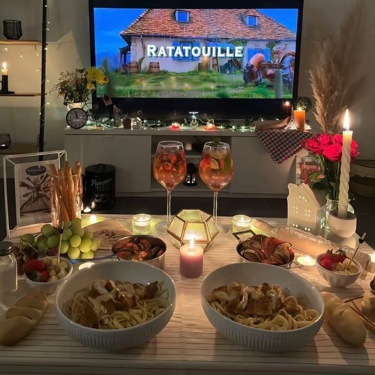 Pasta dinner and drinks set before a TV playing the movie Ratatouille.