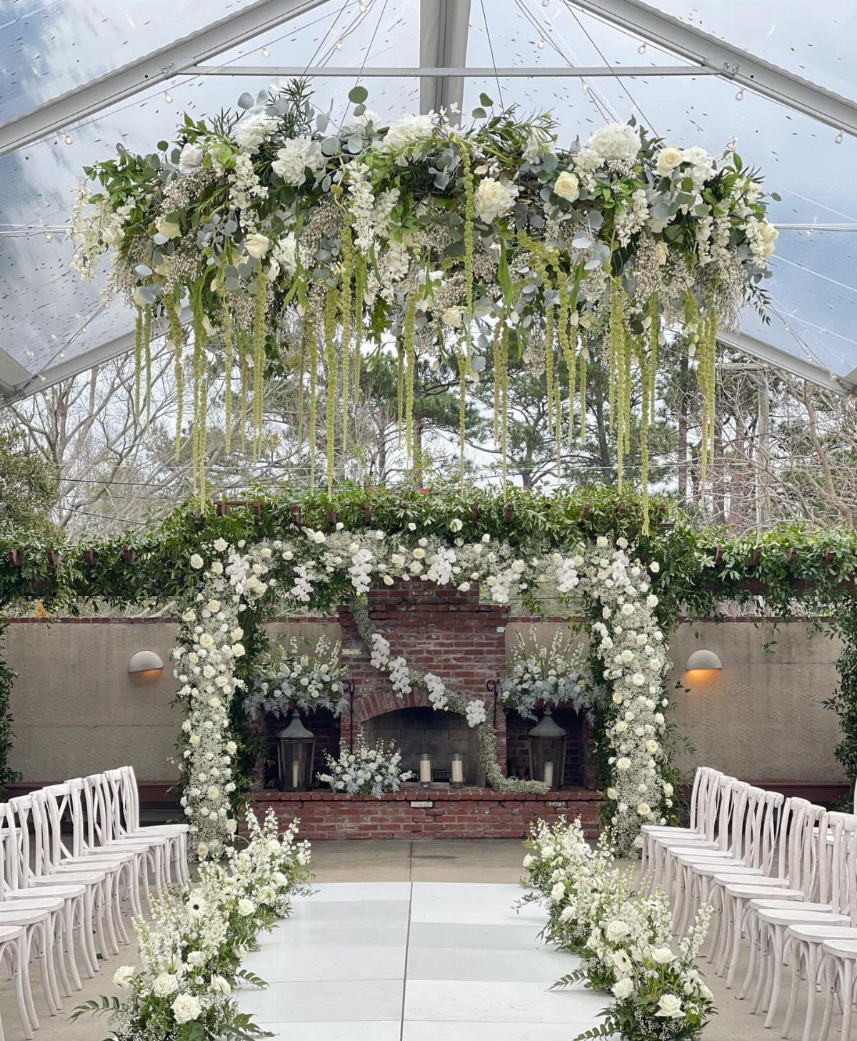 Floral pergola arch with white flowers and greenery over a wedding ceremony aisle