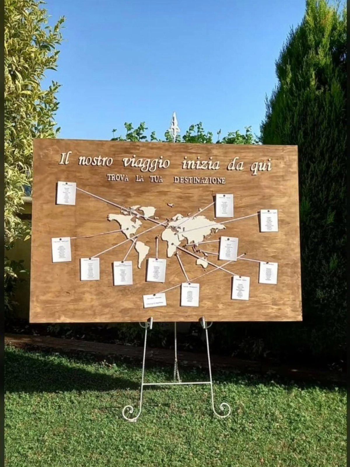 Wooden world map seating chart with white cards connected by strings on easel
