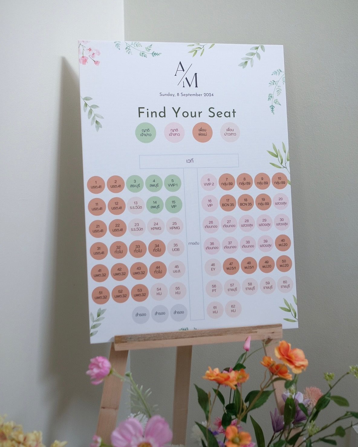 Wedding seating chart on a wooden easel with floral decorations and circular name tags.