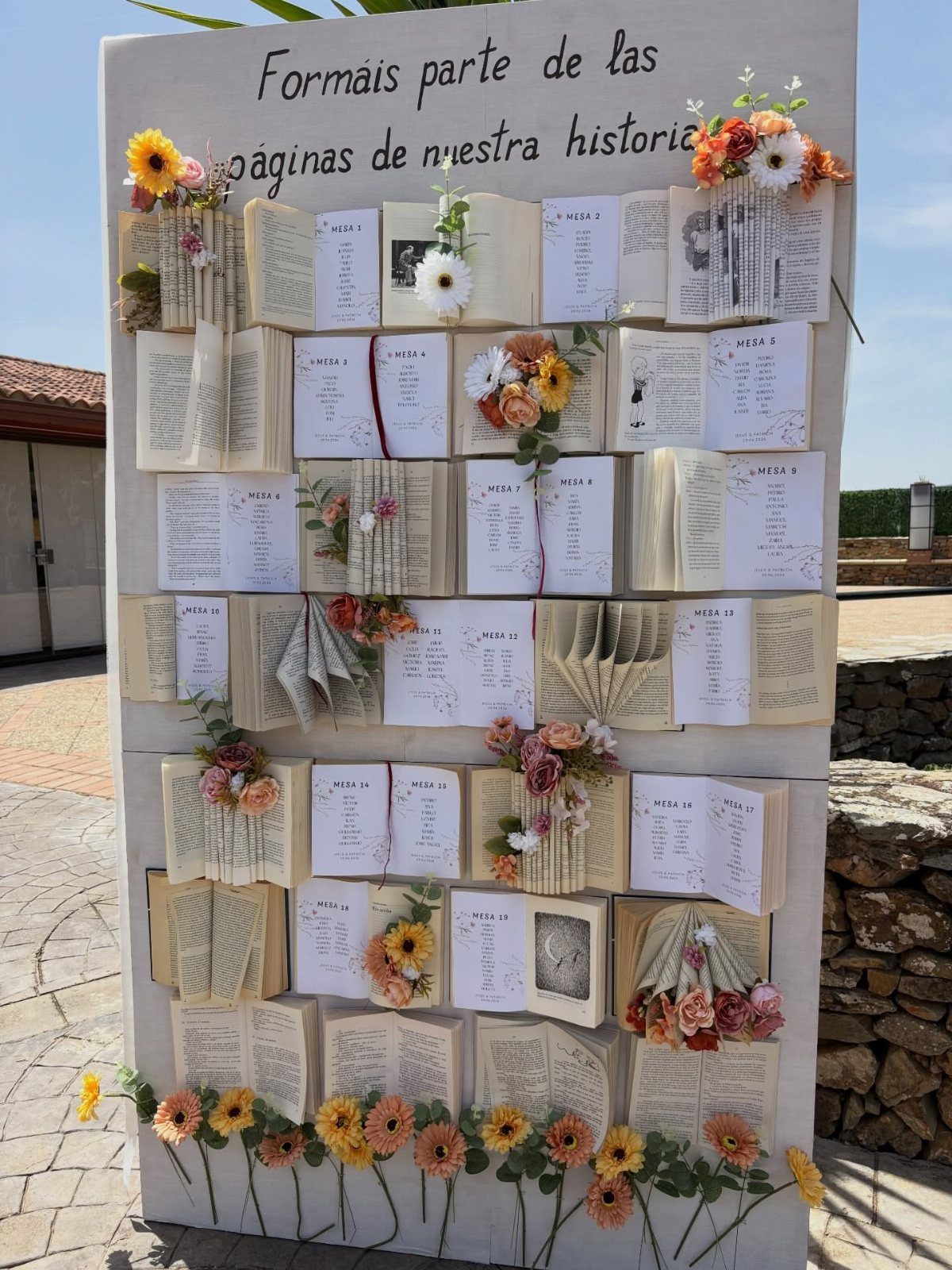 Open books with guest lists and flowers arranged on a white wall.